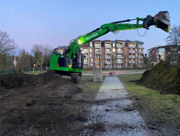 Bagger lagert Mutterboden über Fußweg beim Hügelabtrag in Hamburg Volksdorf